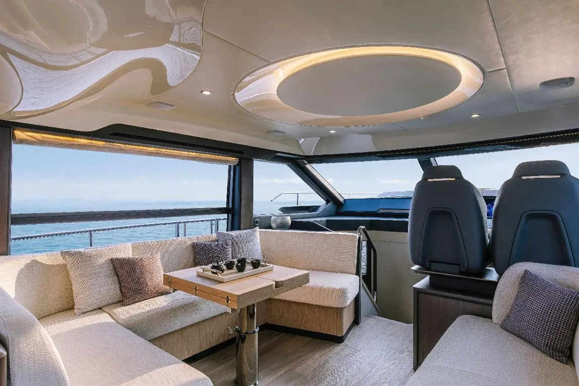 Luxurious yacht interior with plush seating, a central table, and panoramic windows overlooking the ocean view.